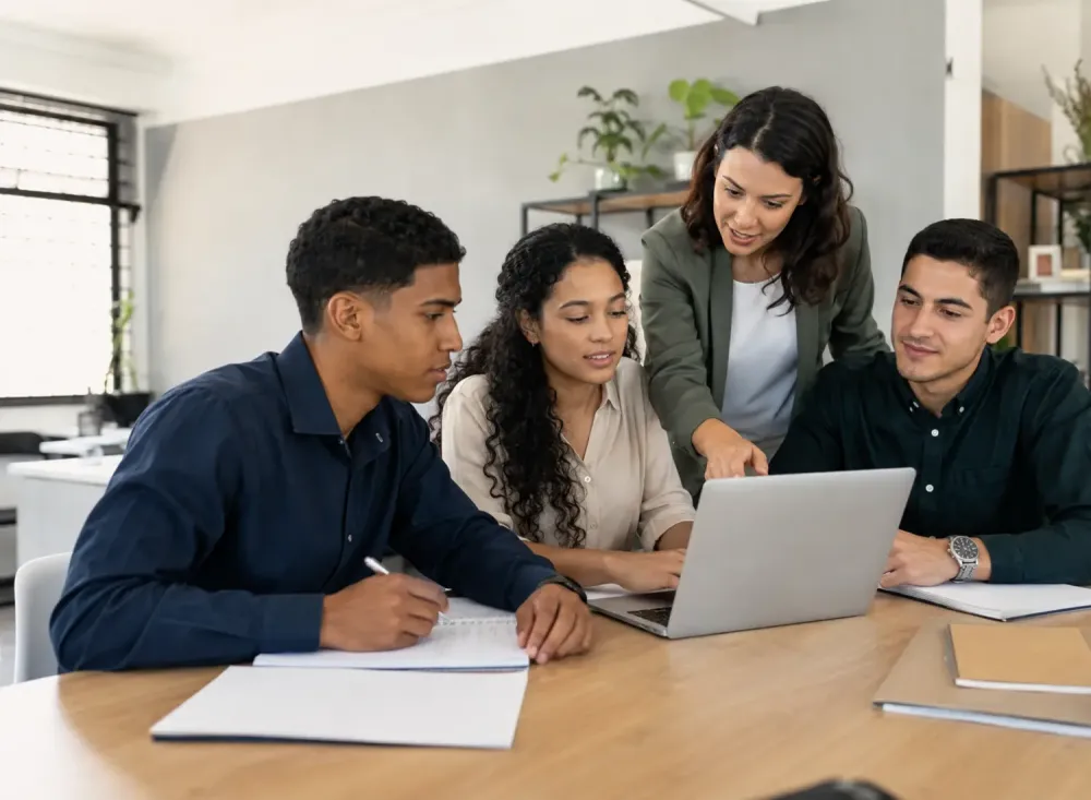 Jovens adultos participando de uma capacitação administrativa em ambiente de escritório, acompanhados por uma profissional mais experiente. A cena representa o aprendizado prático e teórico oferecido pelo programa.